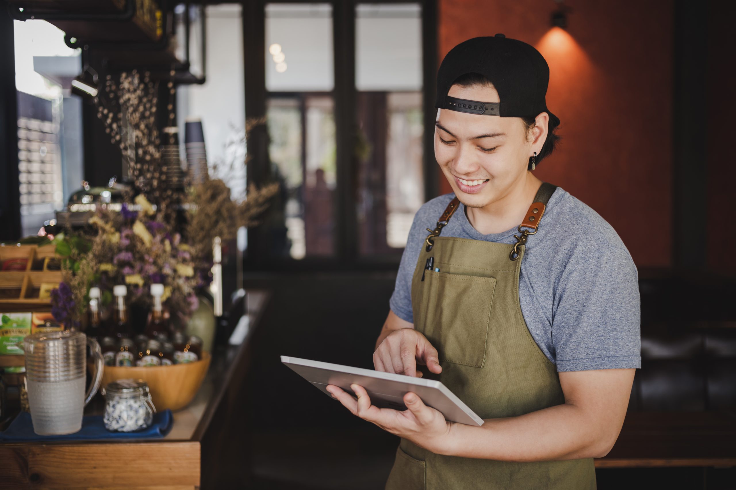 asian man barista holding tablet for checking order from custome